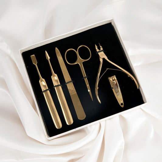 professional manicure tools. on a white background, a six piece gold manicure set is laid out.